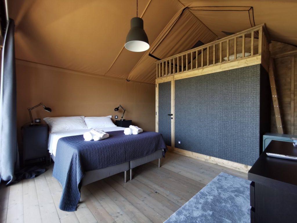 interno con letto matrimoniale e soppalco in legno in un glamping